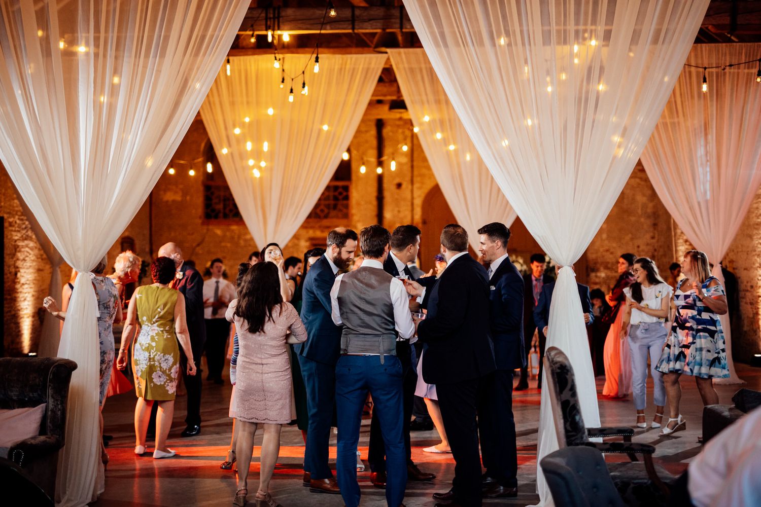 Wedding reception space with elegant white fabric draping and warm ambient lighting.