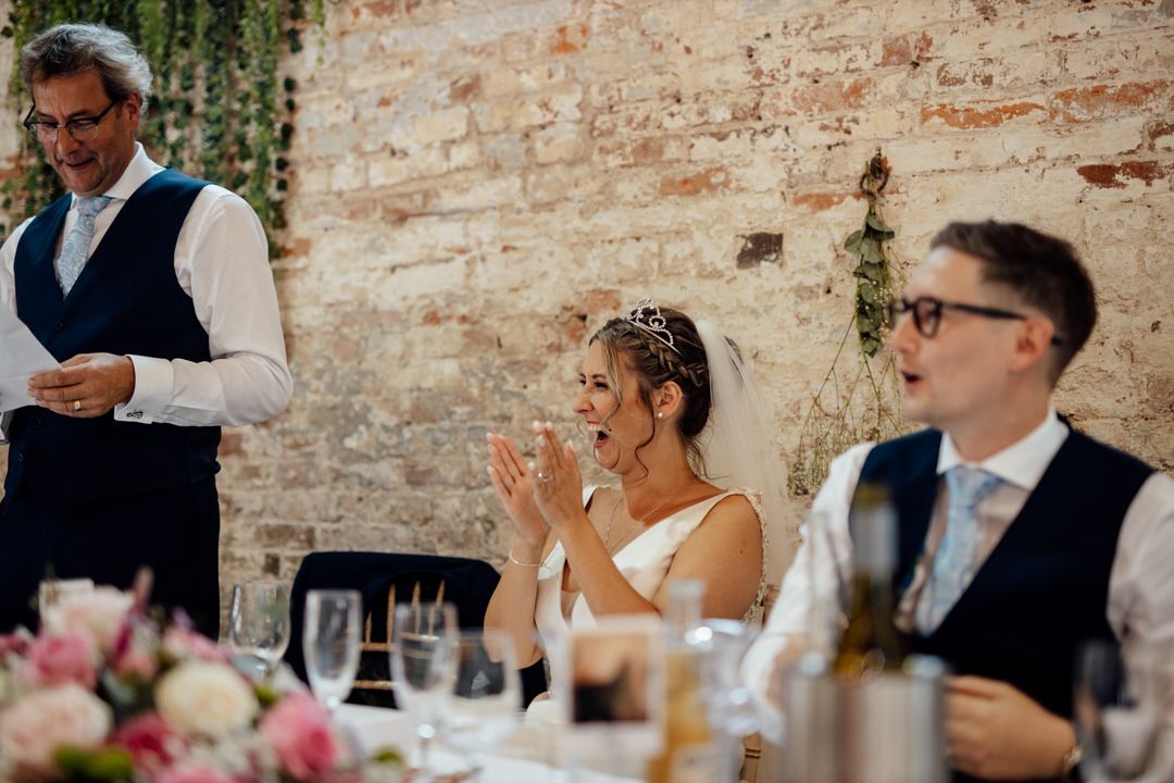 Wedding reception celebration in a rustic brick venue with floral centerpieces and elegant decor.