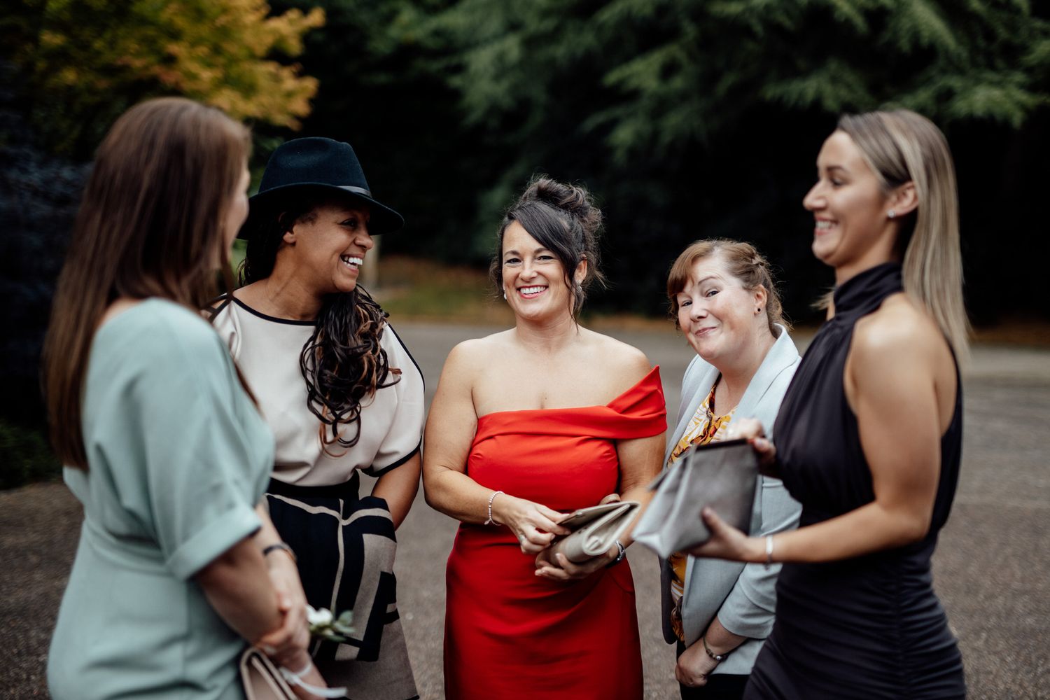 Wedding party members laughing together outdoors in casual group poses.