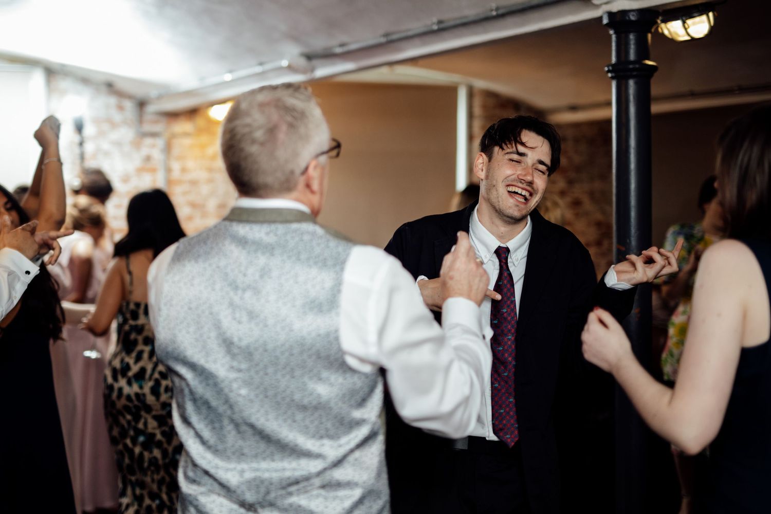 Wedding guests dancing and celebrating at an indoor reception venue.