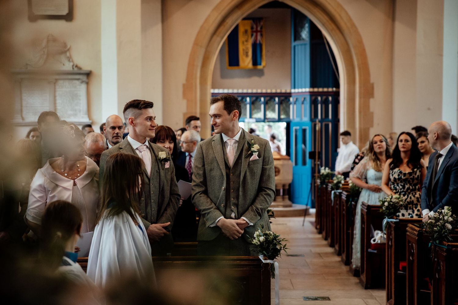 Wedding ceremony taking place in a historic church with stone arches and wooden pews.