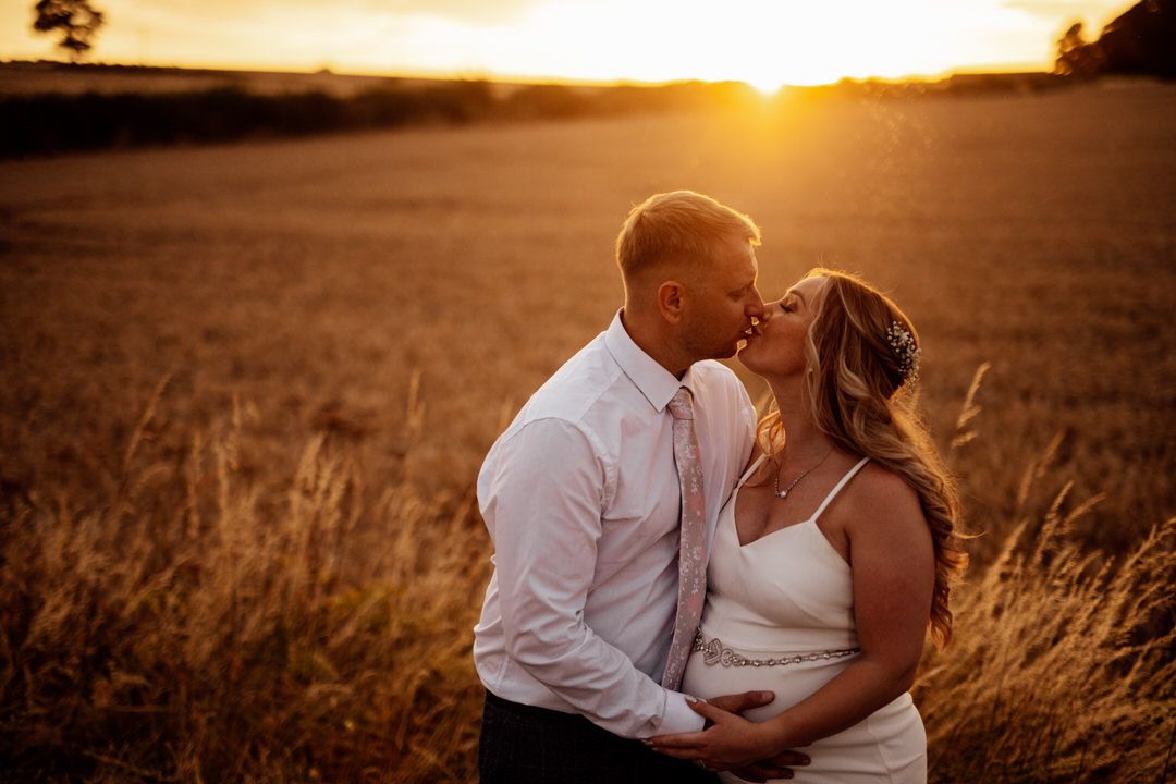 Sunset silhouette of a couple embracing in a golden field during their wedding photoshoot.
