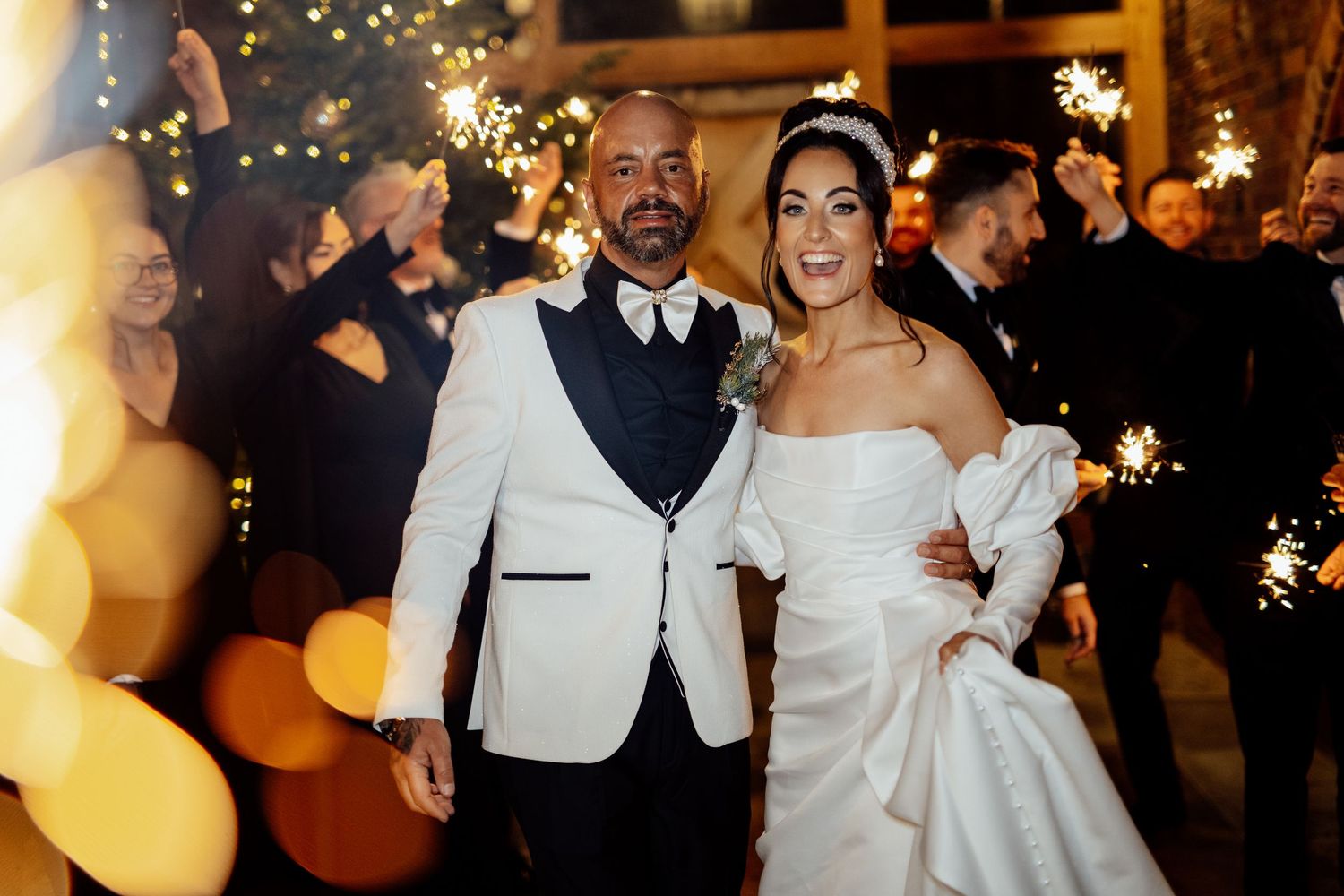 Wedding party celebrates with sparklers creating a magical nighttime atmosphere.