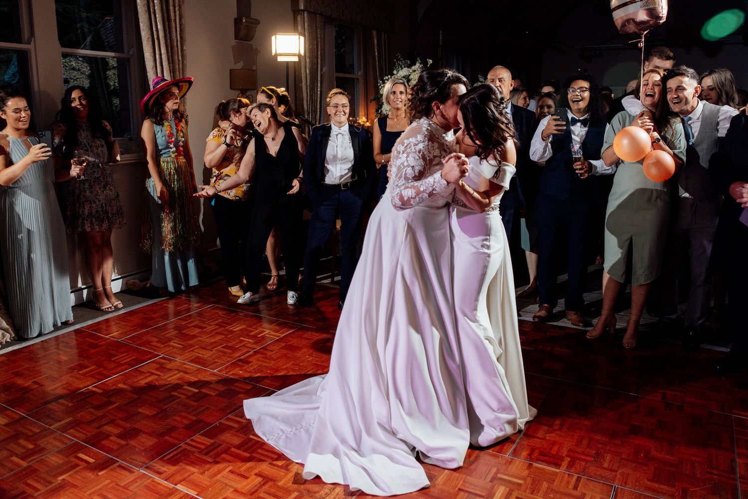 Wedding guests dancing on a wooden dance floor during evening reception festivities.