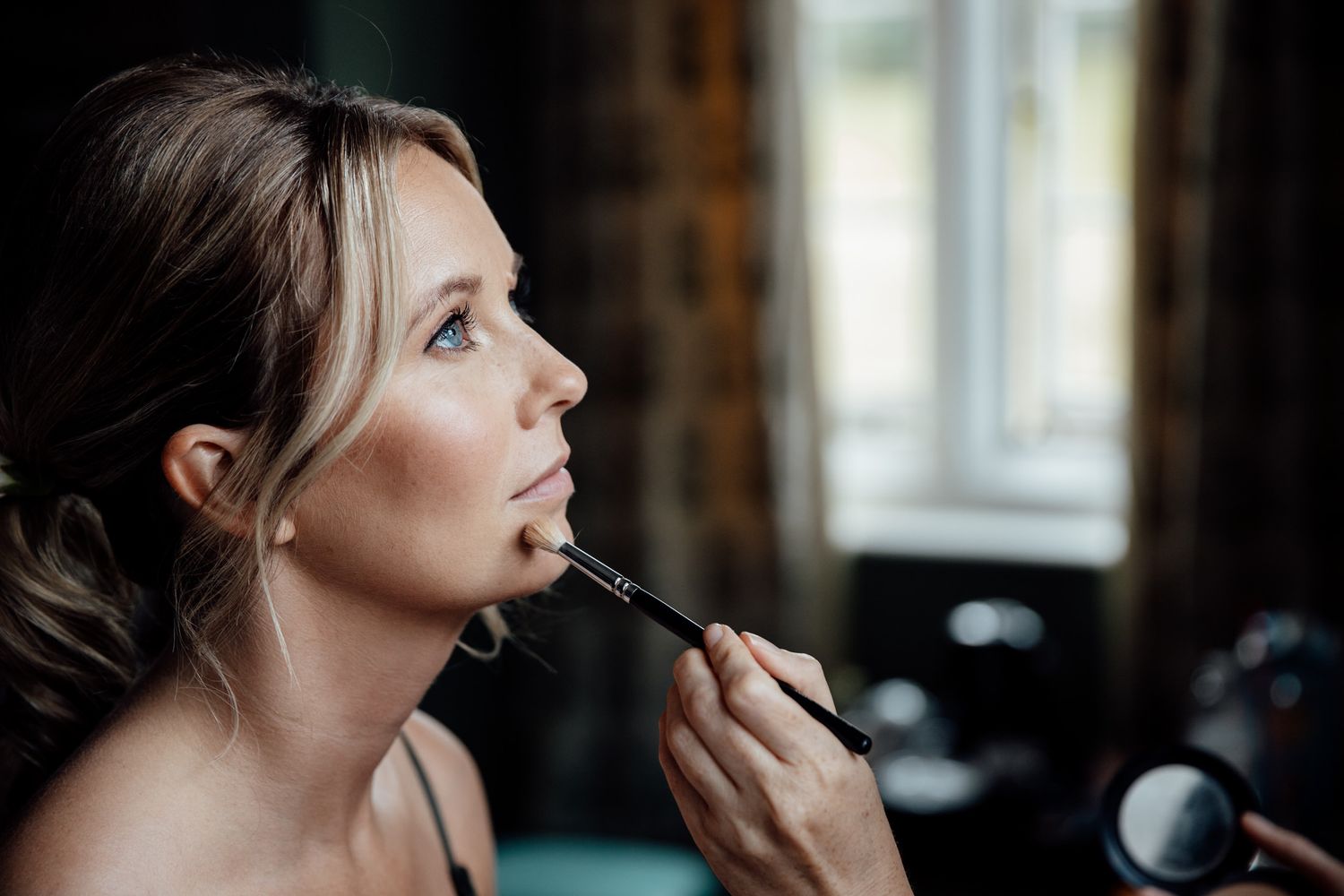 Close-up shots of wedding day makeup application in natural window light.