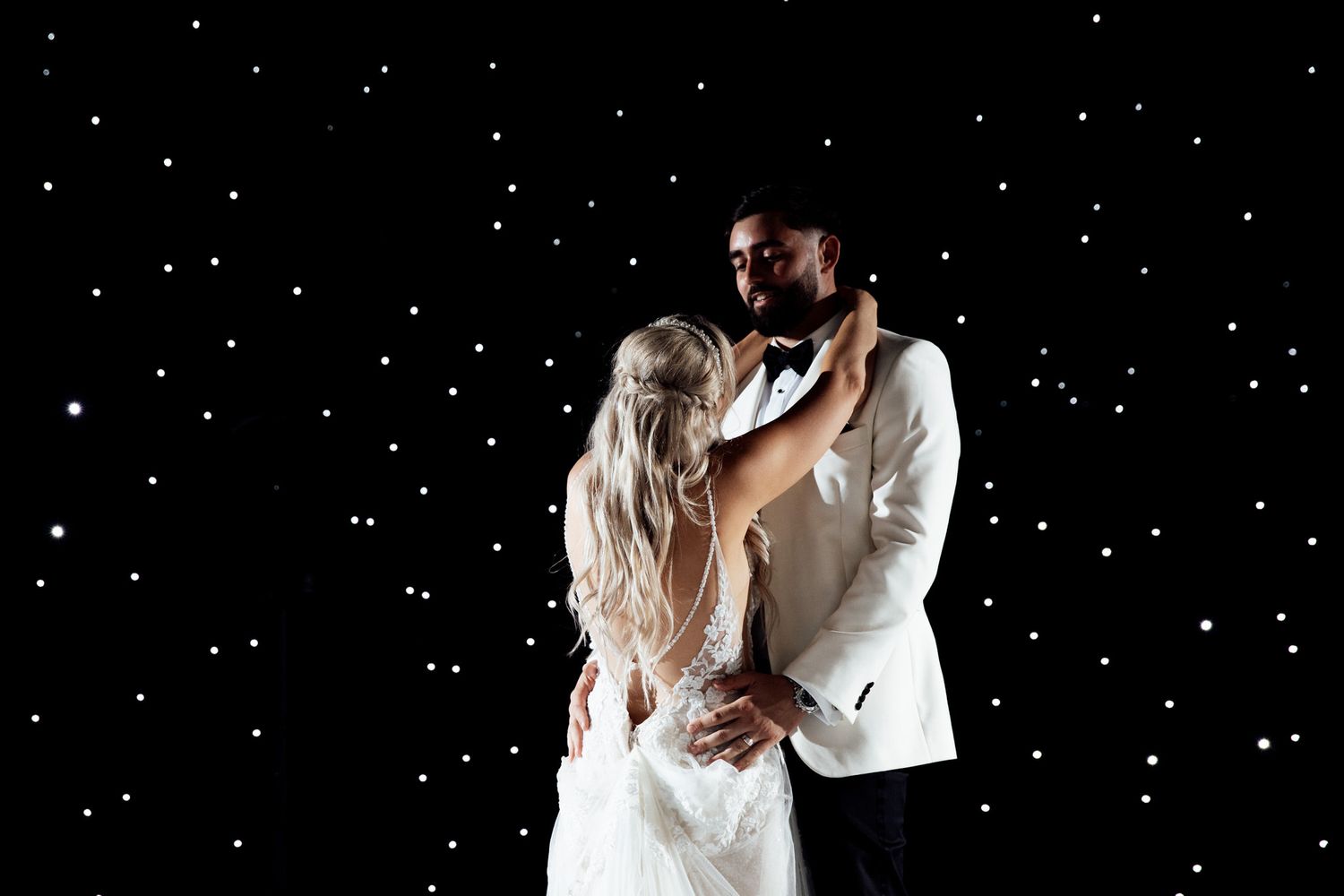 Romantic dance under twinkling starlit backdrop at wedding reception.