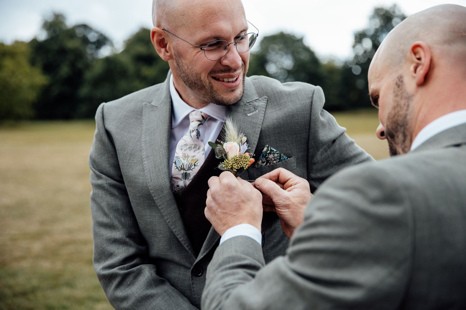 Groomsmen in gray suits adjusting ties and boutonnieres before the ceremony.