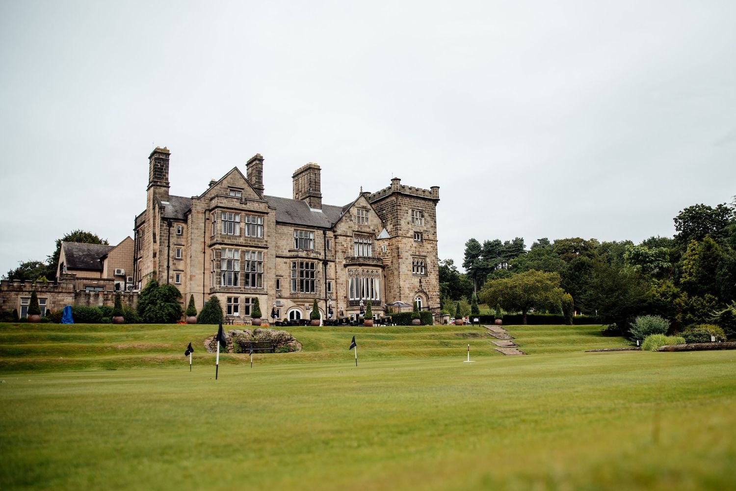 Majestic stone manor house with expansive green lawn and Gothic architectural details.