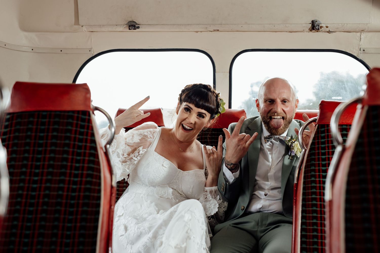 Wedding party posing and laughing together in vintage red theater seats.