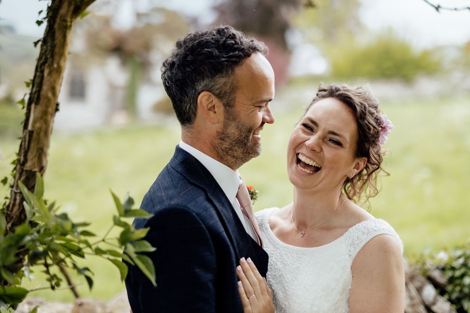 A joyful wedding moment captured outdoors with natural greenery in the background.