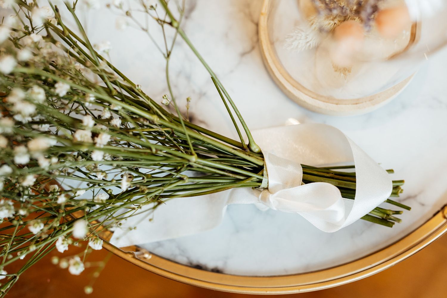 Elegant floral arrangements with white roses and greenery in glass vases on a table setting.