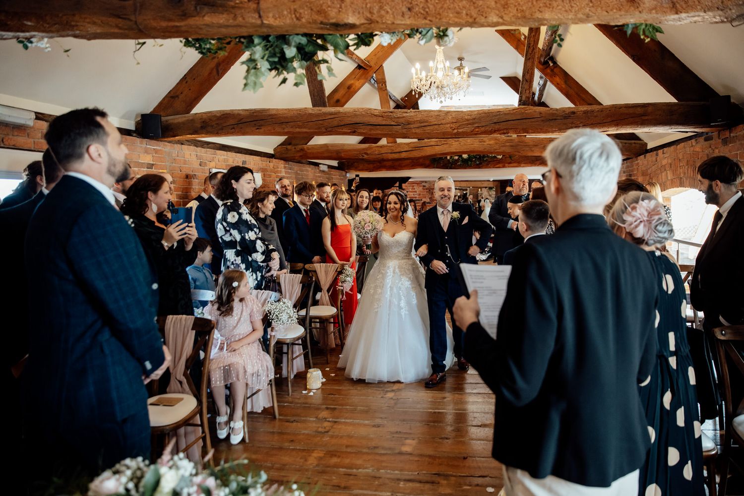 Wedding reception in a rustic barn venue with exposed wooden beams and natural light.