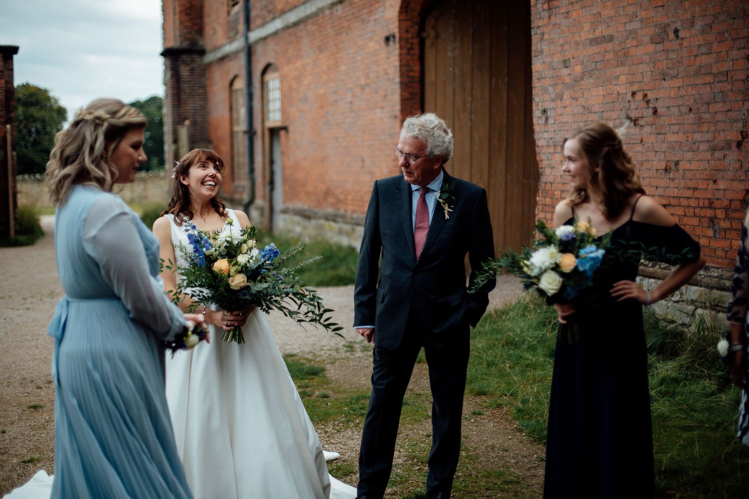 Wedding celebration moments captured against a historic brick wall exterior.