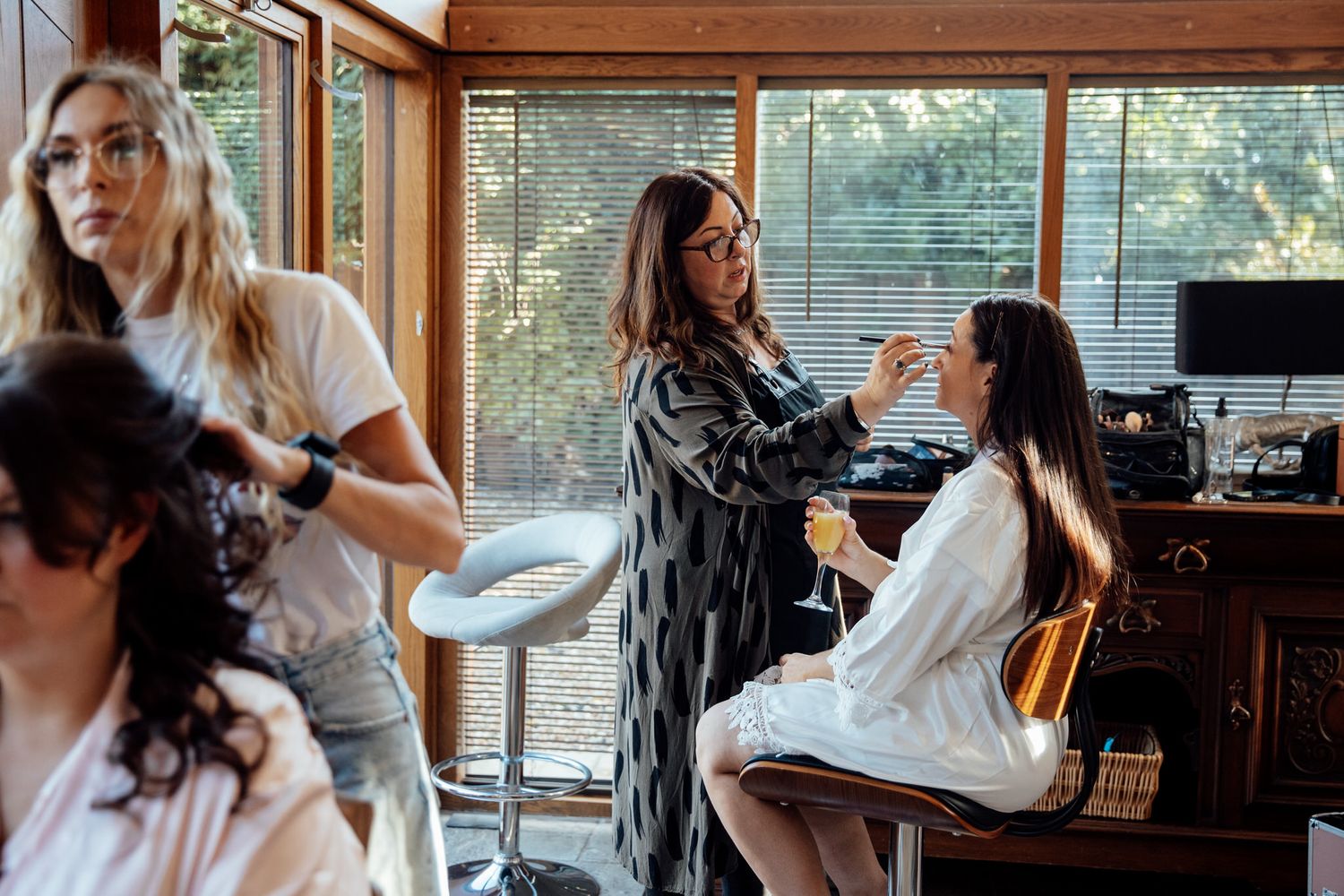 Wedding preparation scene in a bright sunlit room with natural window lighting.