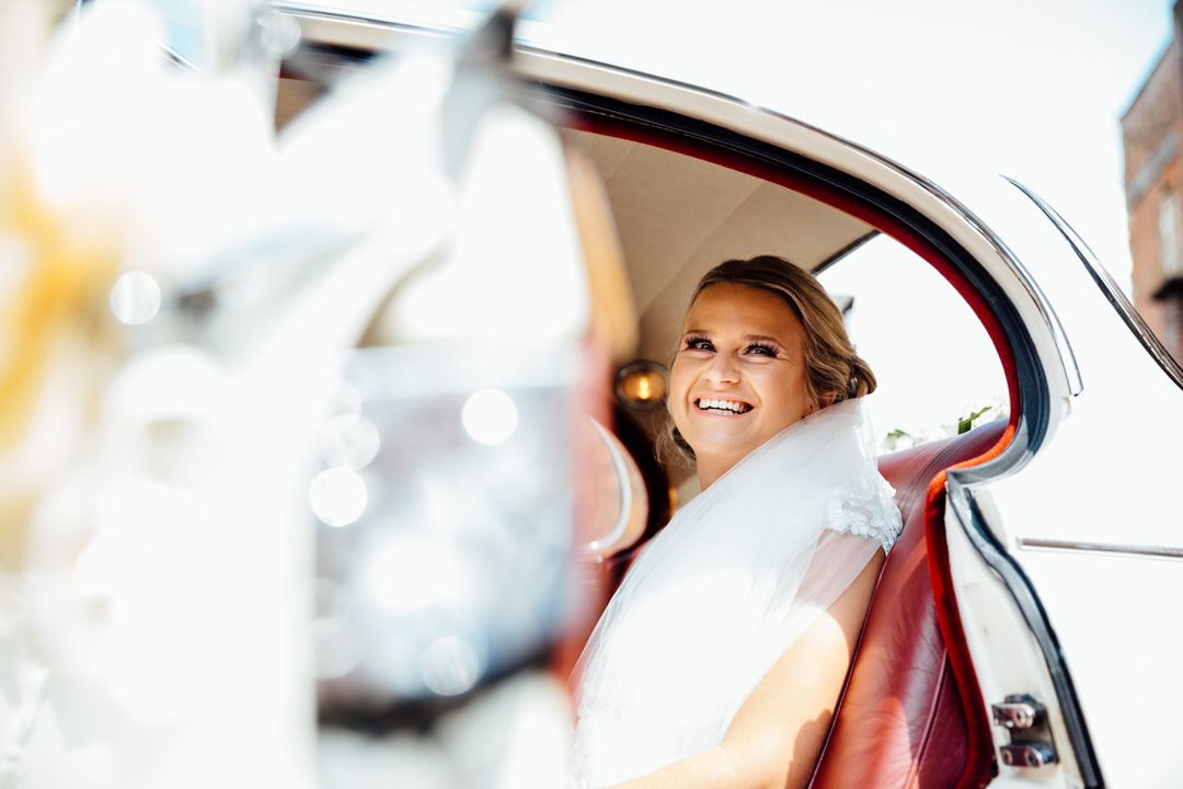 A classic car provides elegant transportation on a sunny wedding day.
