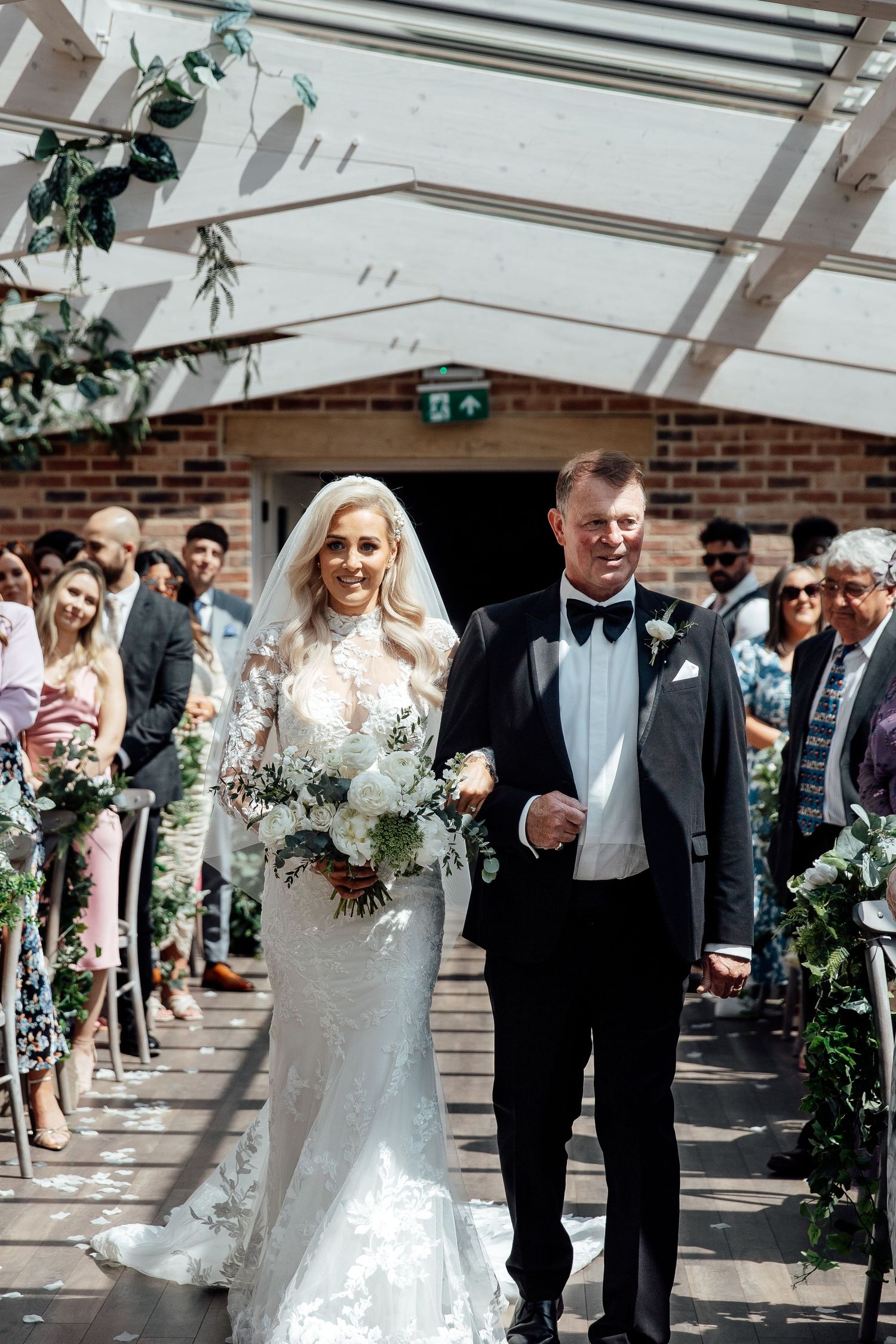 Wedding party walking in procession along a brick building exterior.