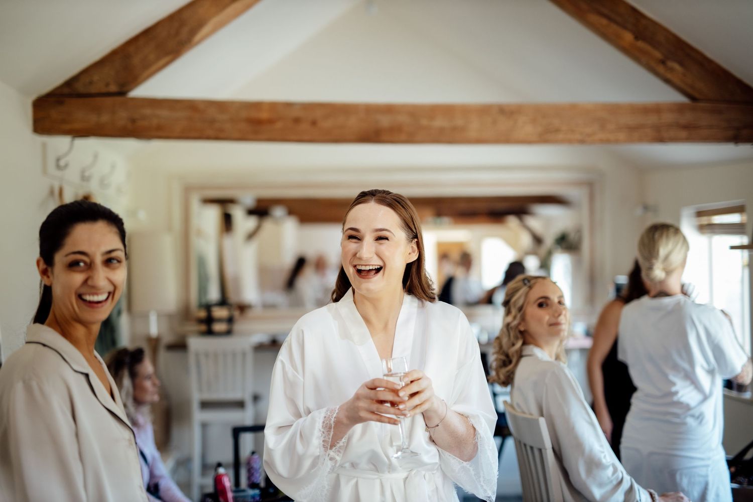 Wedding preparation scene with guests in bright interior space with wooden beams.