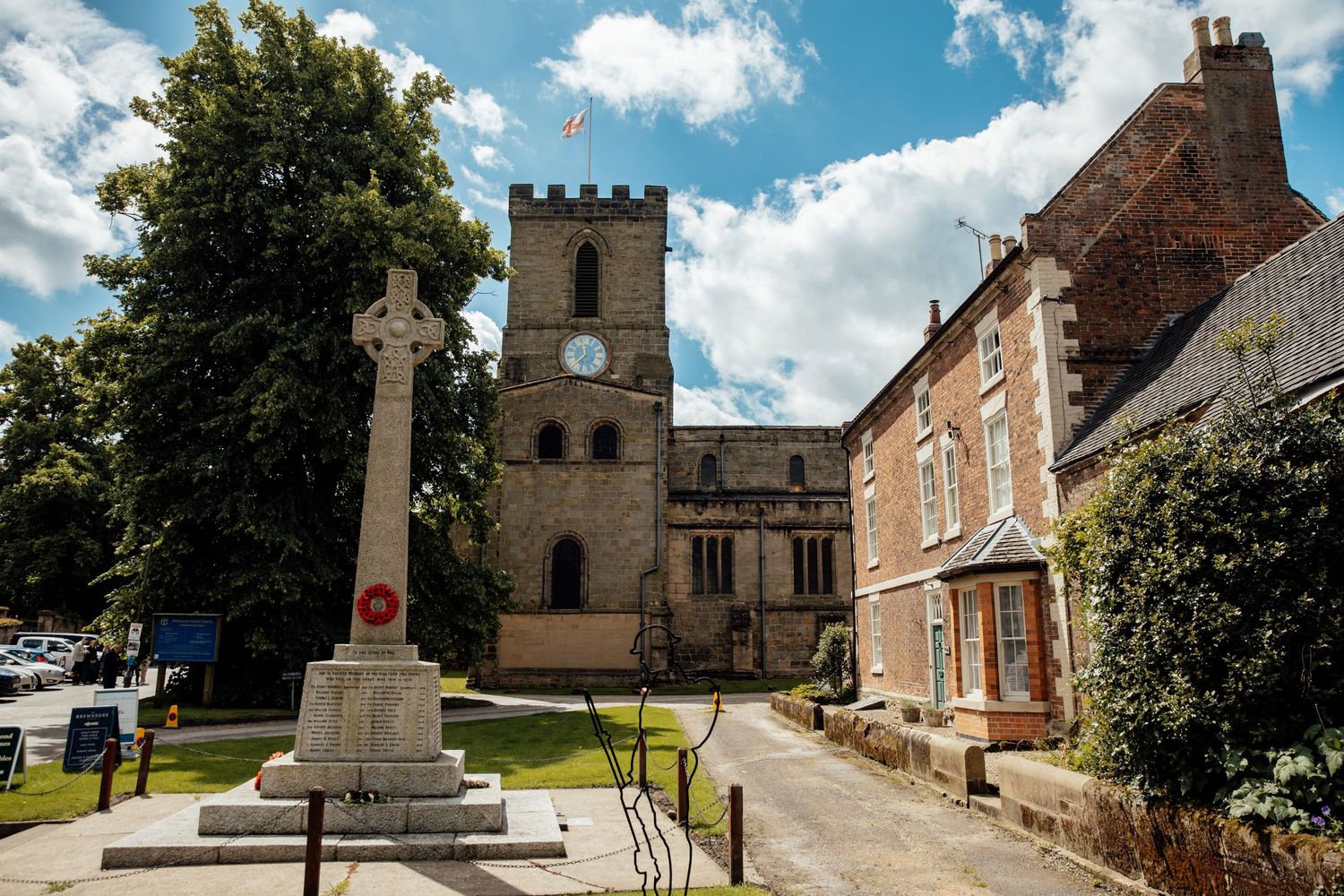 Exterior of a historic stone church and grounds under blue summer sky.