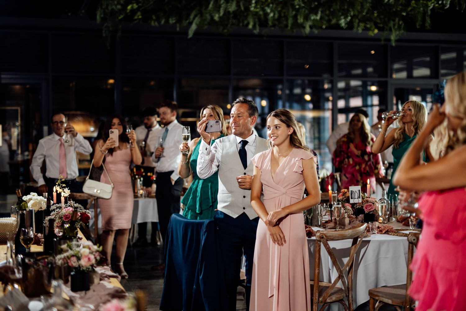 Wedding reception guests dancing and celebrating in dimly lit rustic venue.