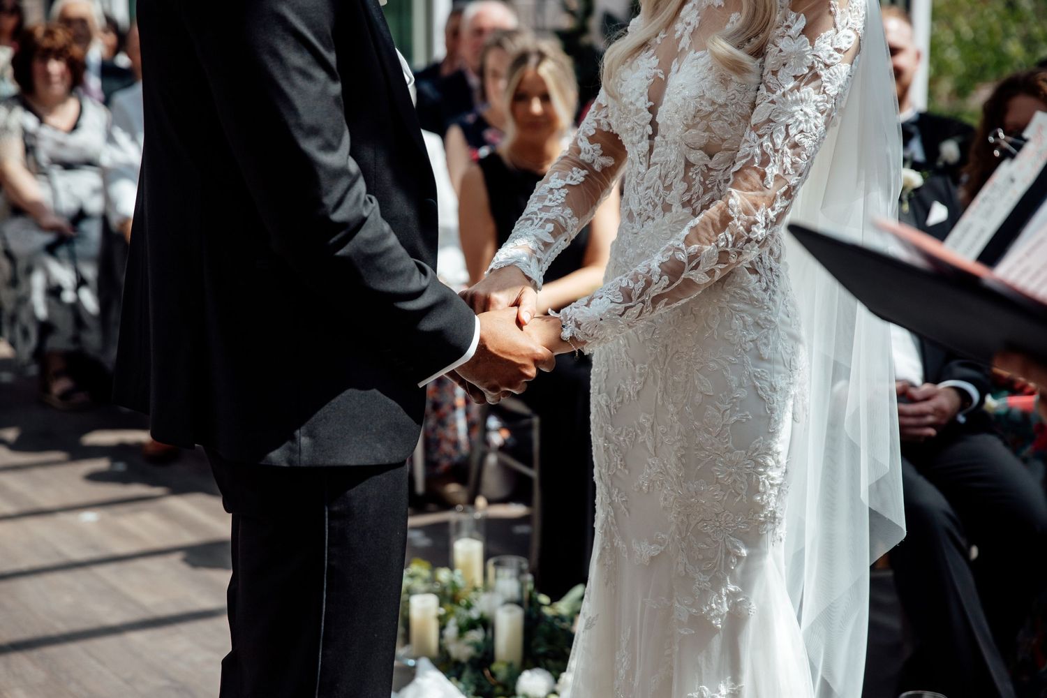 Wedding ceremony in progress with white lace dress details and formal attire.