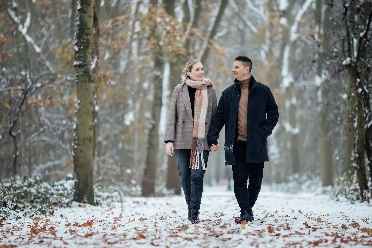 Romantic winter engagement photos captured in a serene snow-covered woodland setting.
