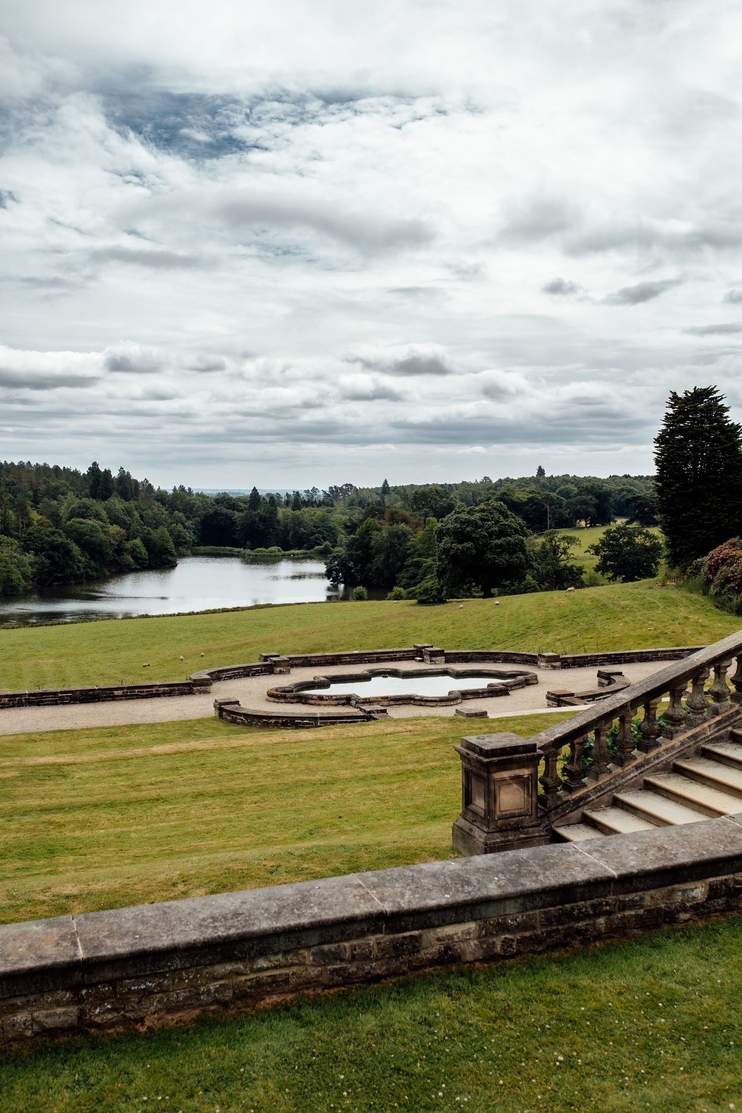 Panoramic view of a lake and rolling hills from a stone terrace on an overcast day.