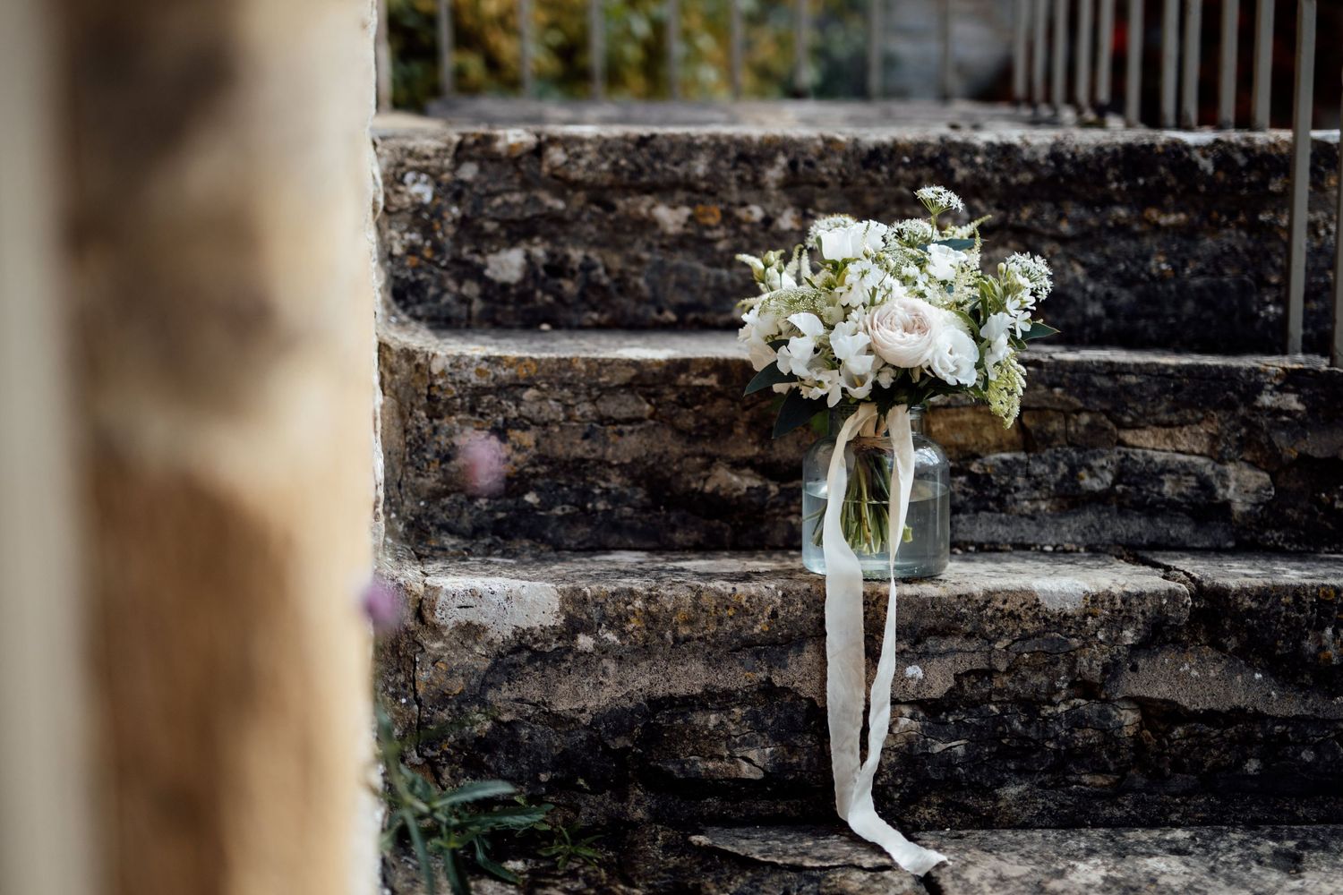 White floral bouquet displayed against weathered stone wall backdrop.