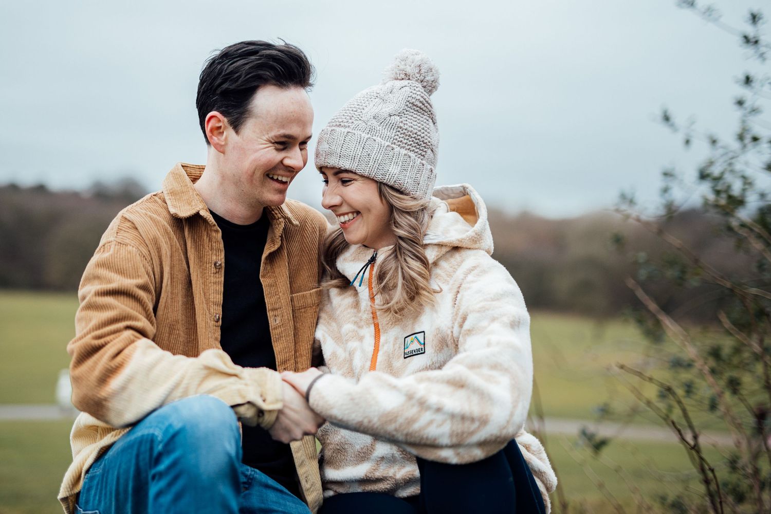 A couple sharing a joyful moment together while sitting outdoors in winter clothing.