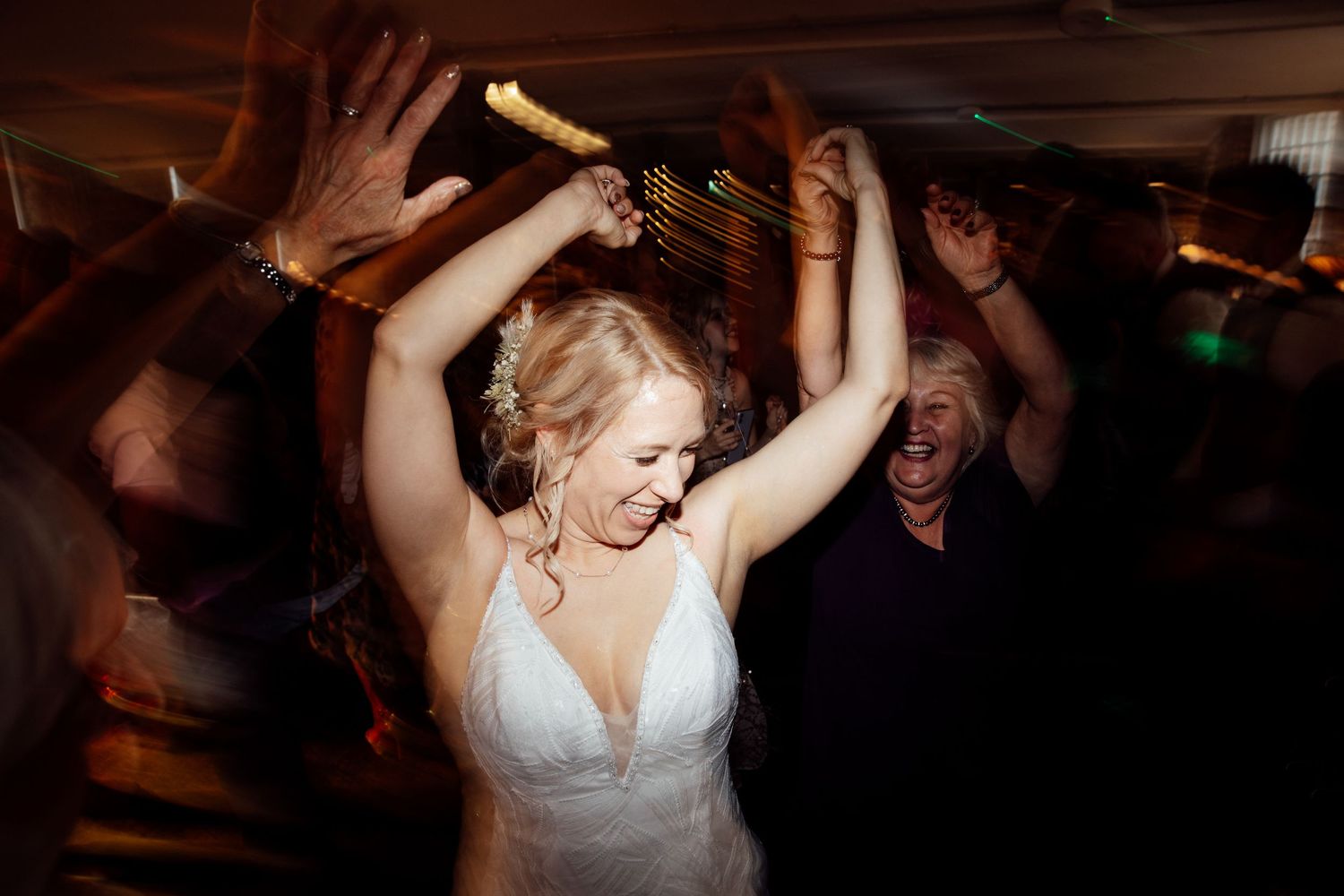 Wedding celebration with dancing and revelry in dimly lit rustic venue.