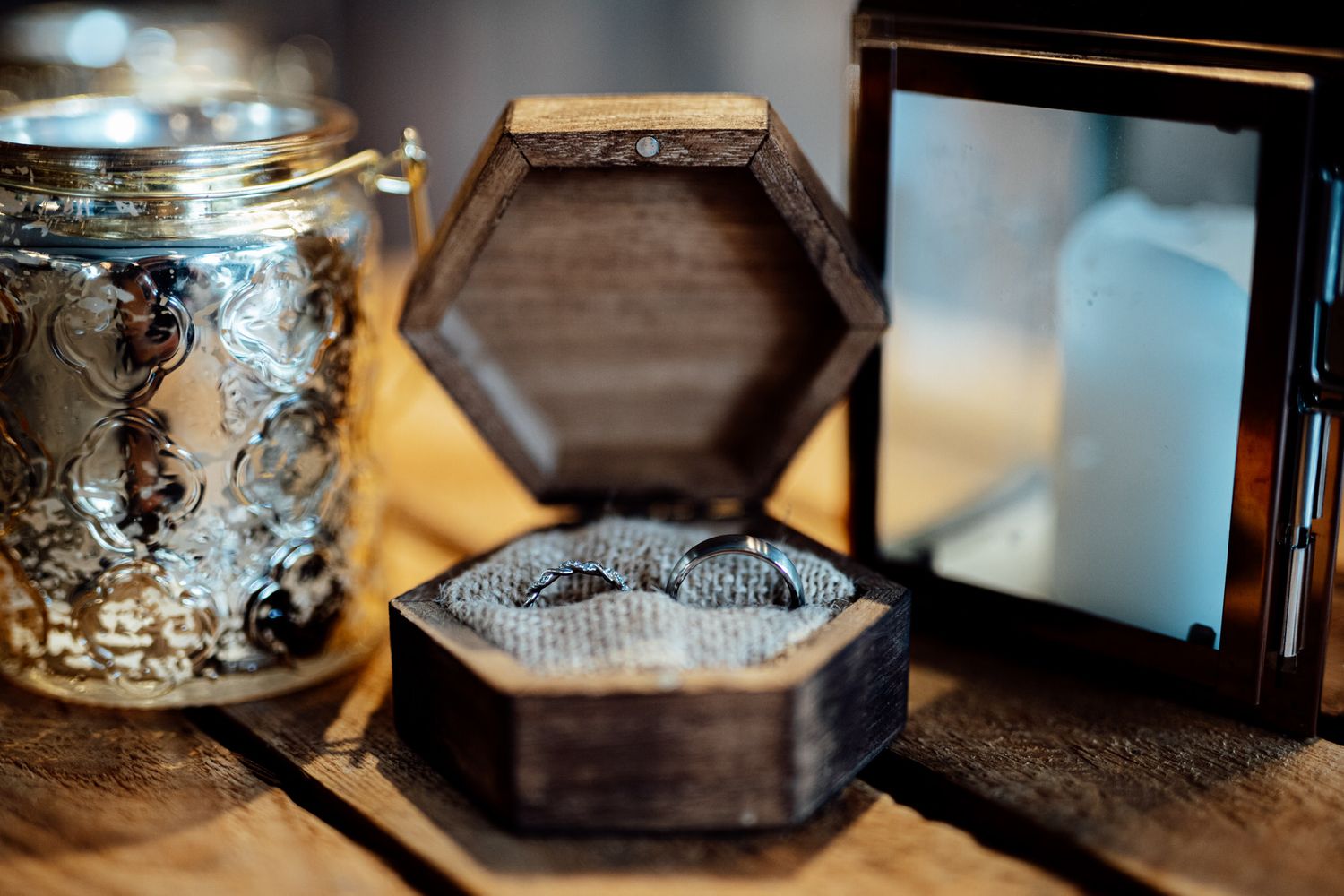 Elegant wedding rings displayed on reflective surface with dramatic lighting.