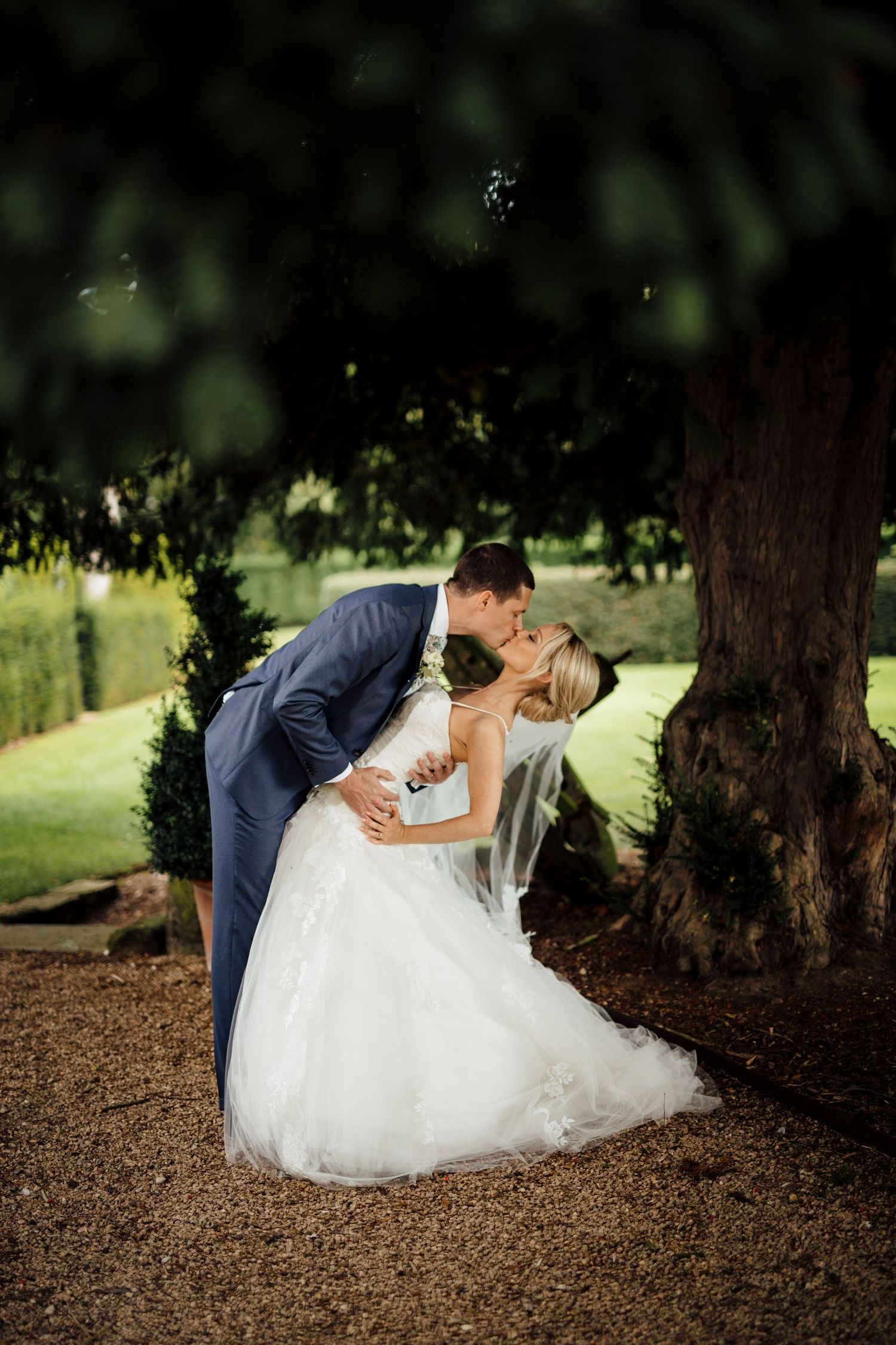 Artistic wedding photography under trees with natural lighting.