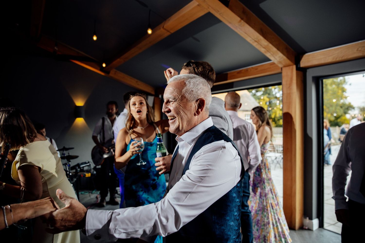Wedding reception venue with exposed wooden beams and ambient lighting.