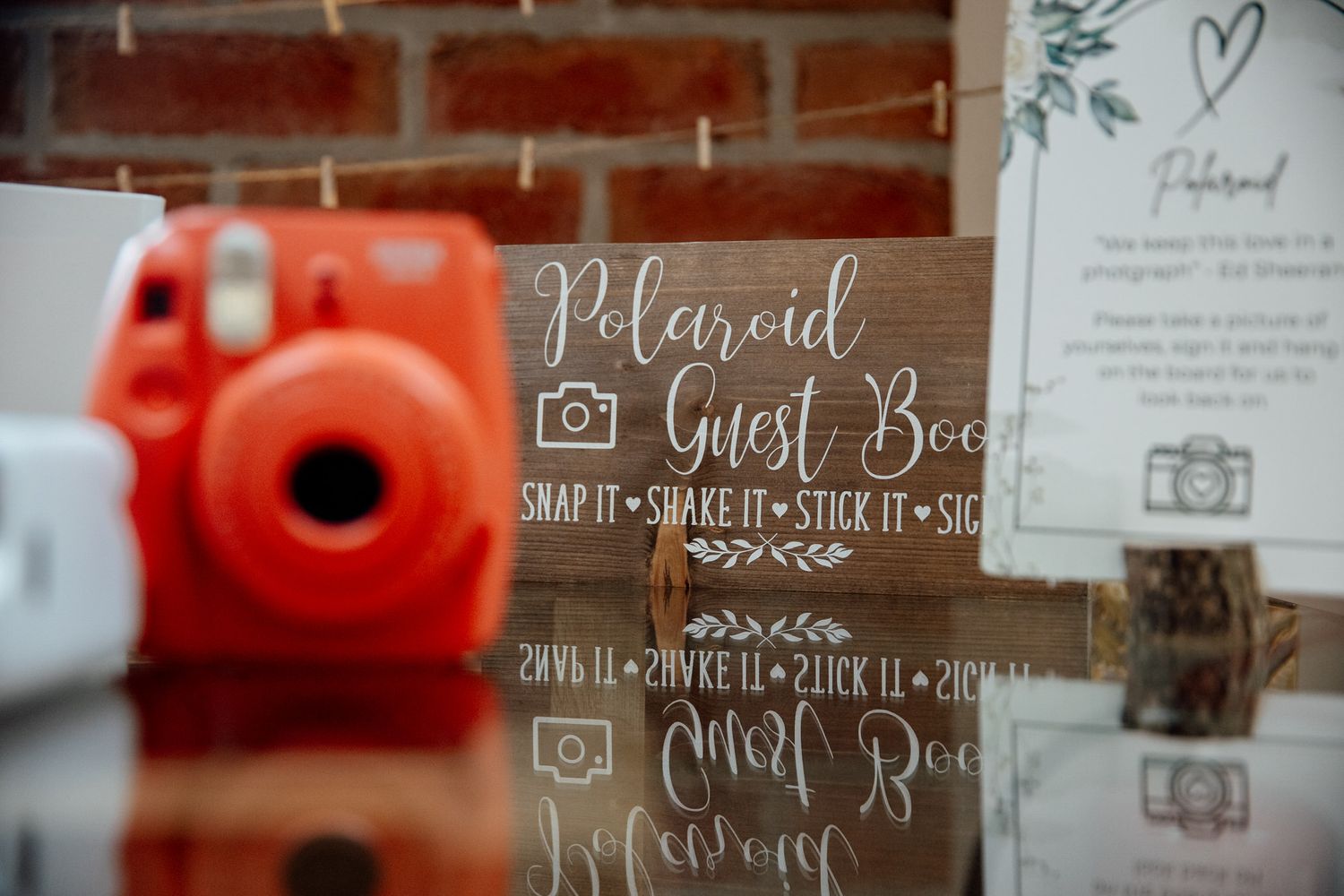 Wooden polaroid guest book sign with red instant camera at wedding reception.