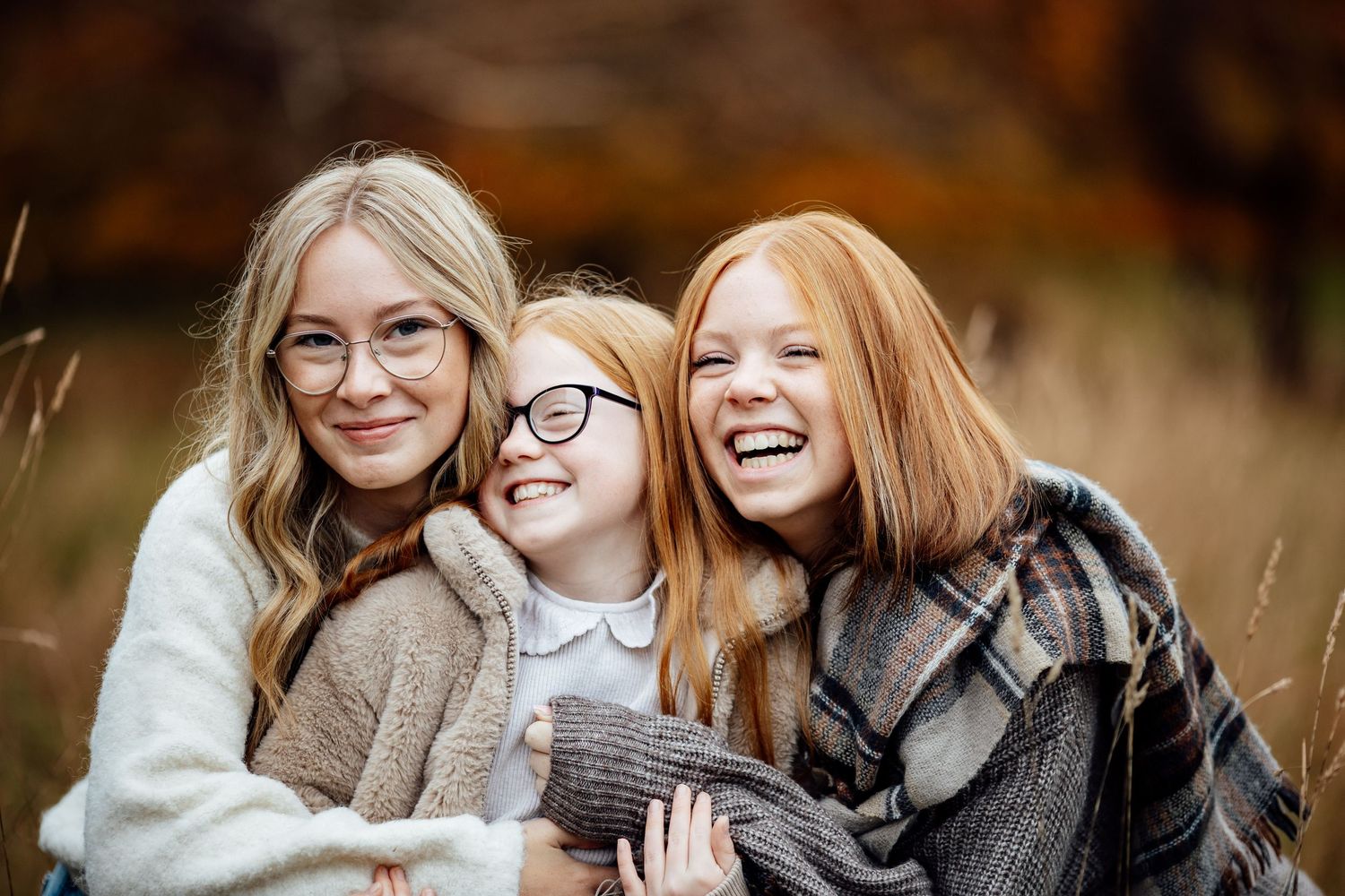 Friends laughing together during an outdoor autumn photoshoot.