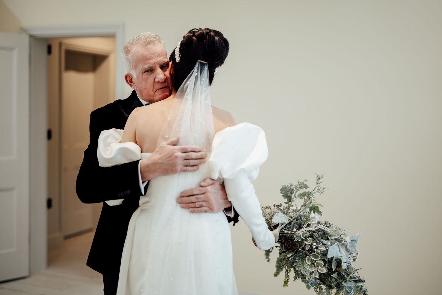 A tender embrace captured during an indoor wedding celebration with white decor and floral arrangements.