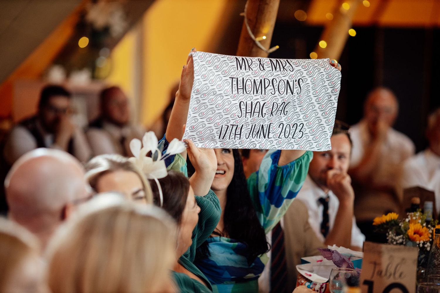 Wedding guests hold up handwritten signs during reception celebration.