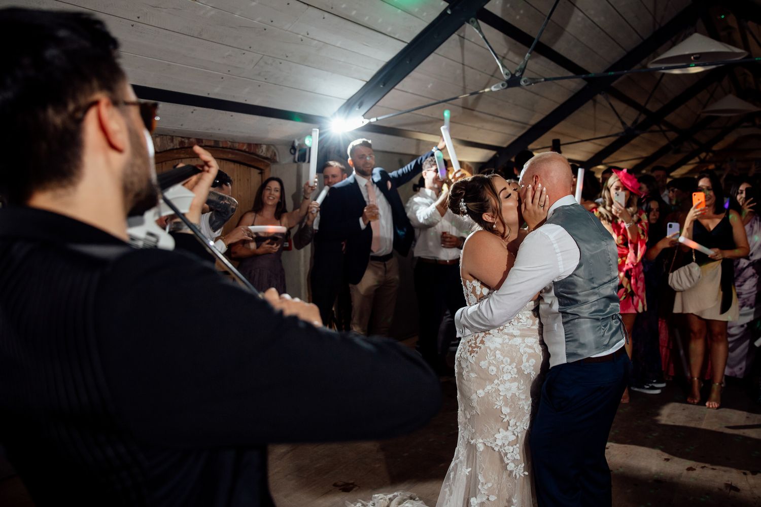 Wedding reception dance floor moments captured in a rustic indoor venue.