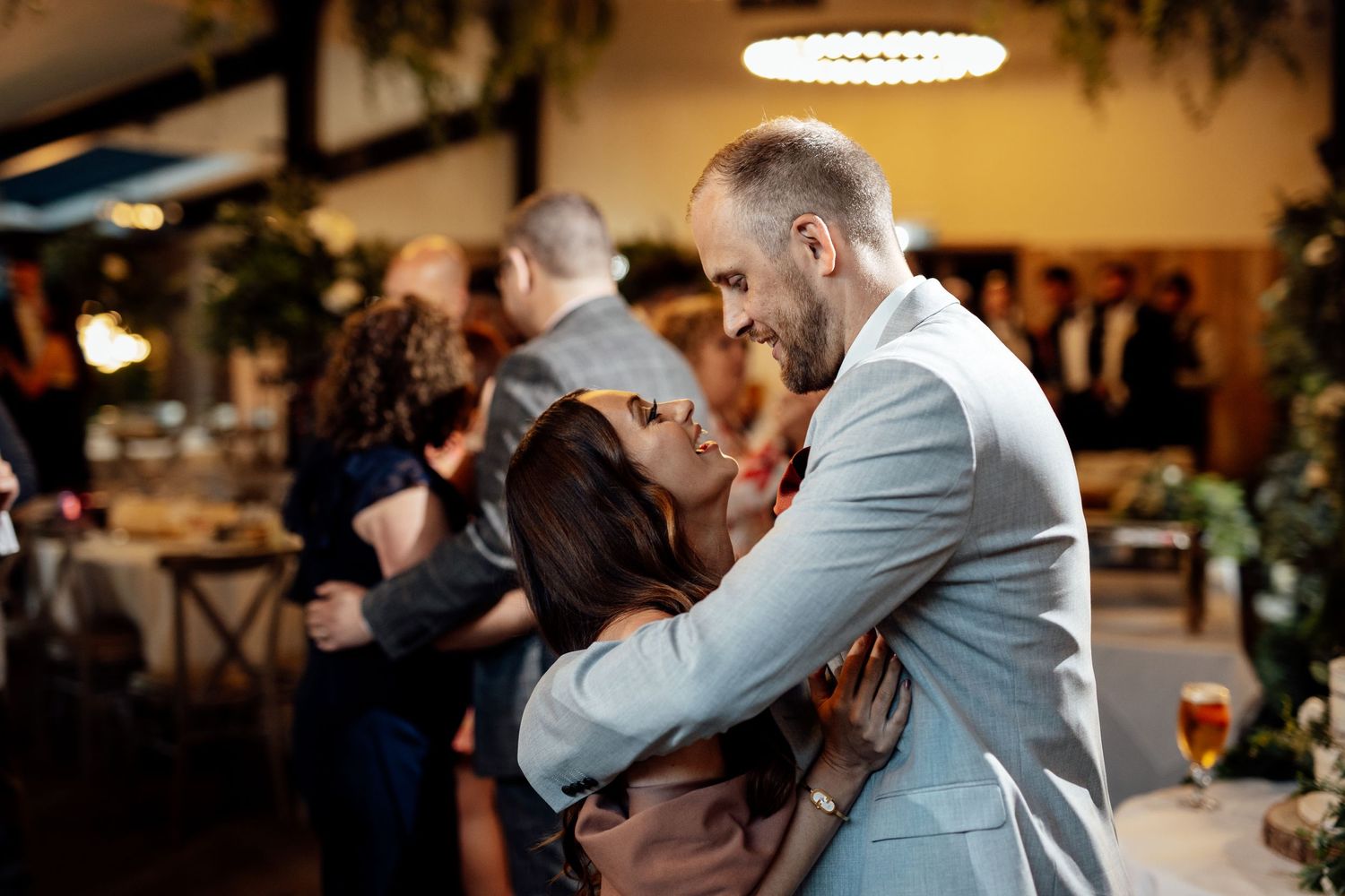 Wedding reception guests celebrate and dance under decorative lighting.