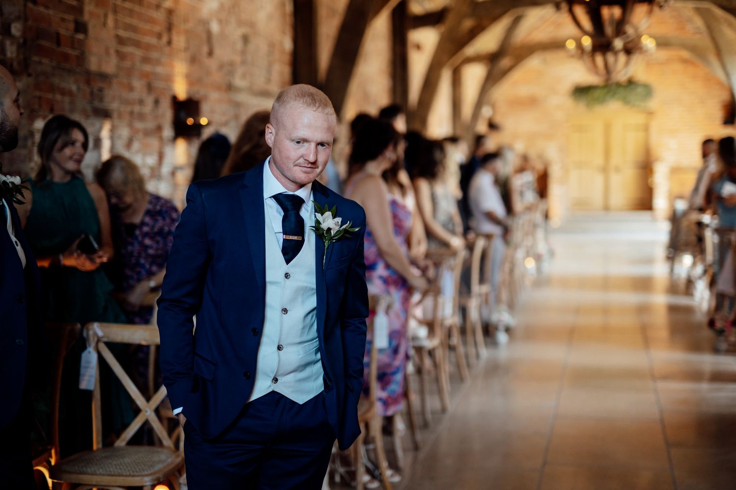 Interior of a rustic brick venue with wooden beams and warm lighting during a ceremony.