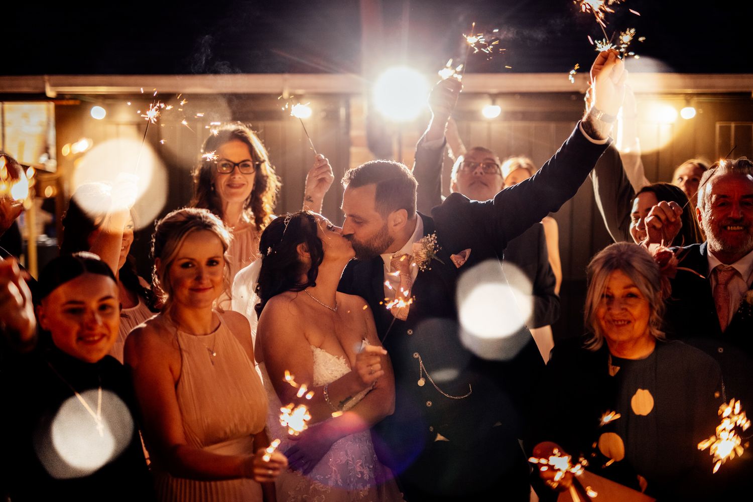 Wedding celebration at night with sparklers creating magical light effects.