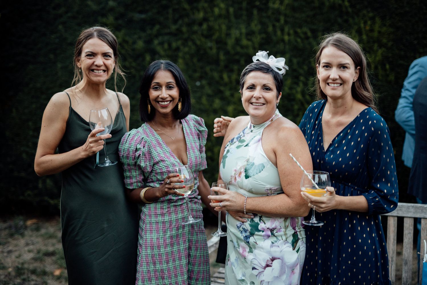 Wedding guests in formal attire enjoying drinks at an outdoor reception.