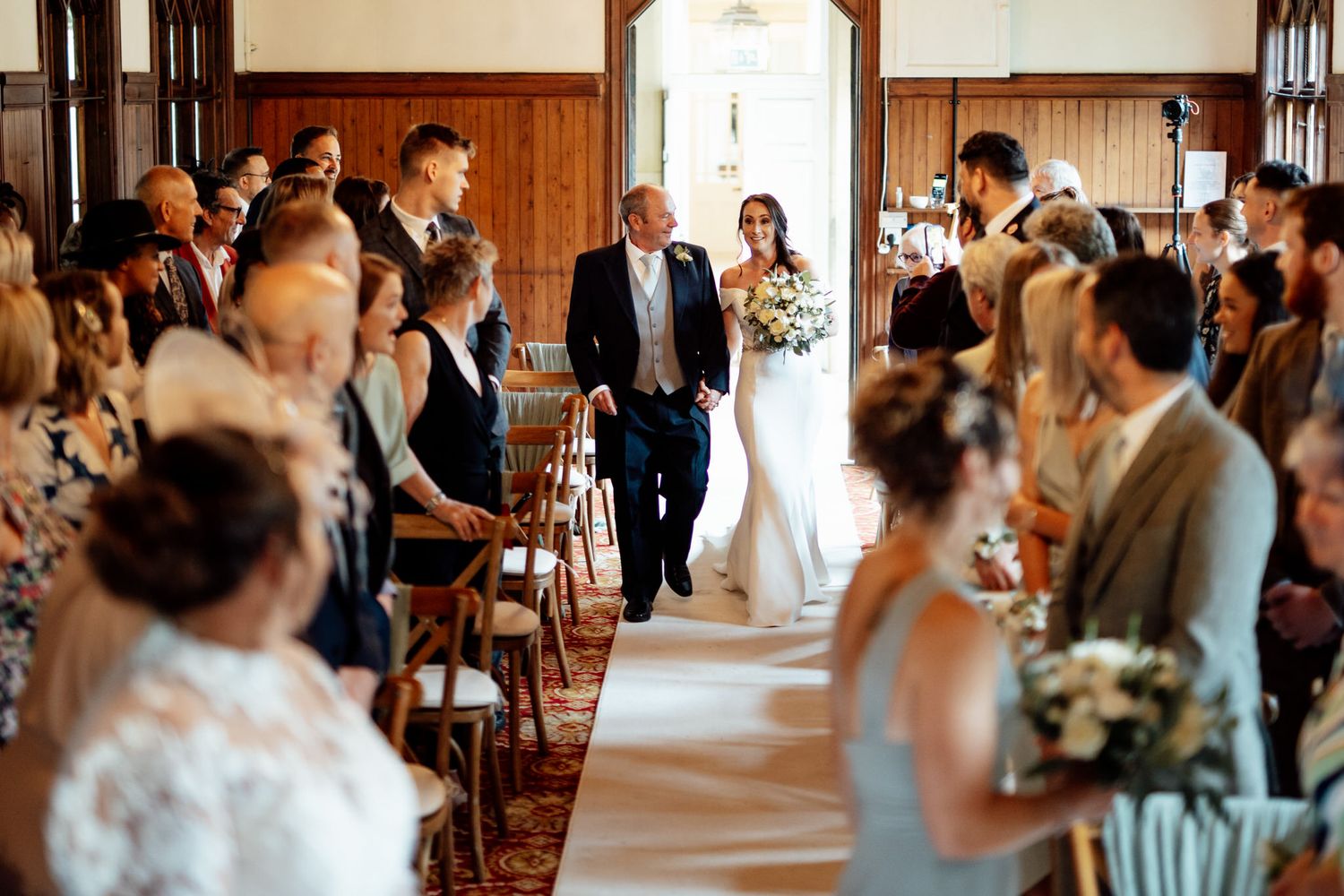 Wedding ceremony and reception moments captured in wood-paneled venue interior.
