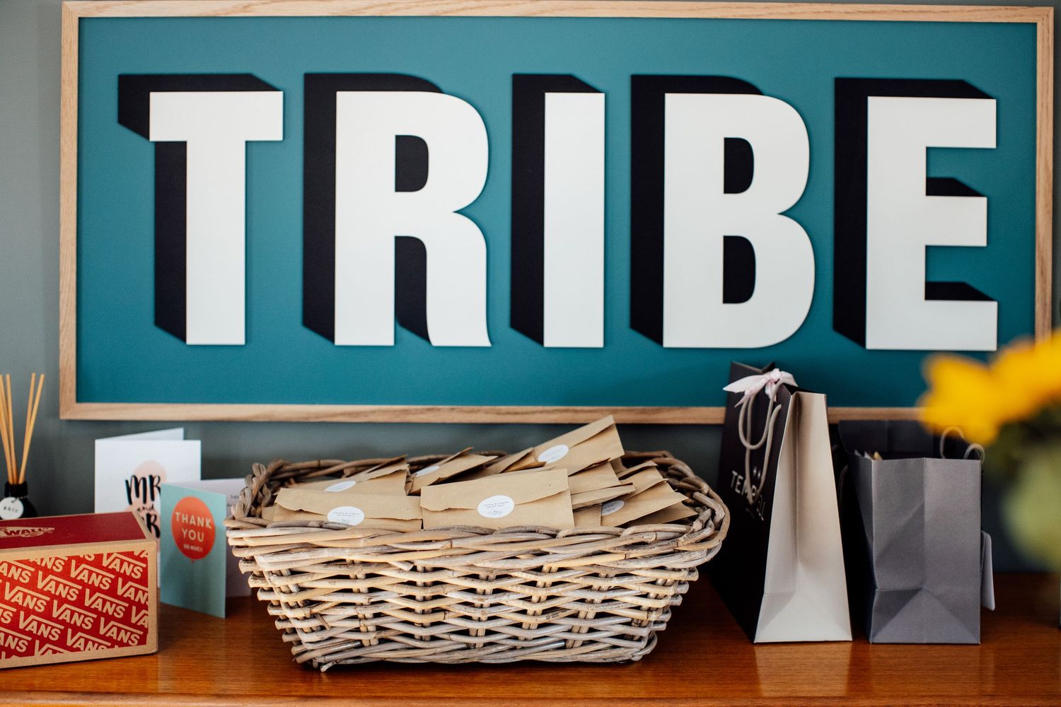 Large decorative letters spelling 'TRIBE' displayed on a turquoise background.