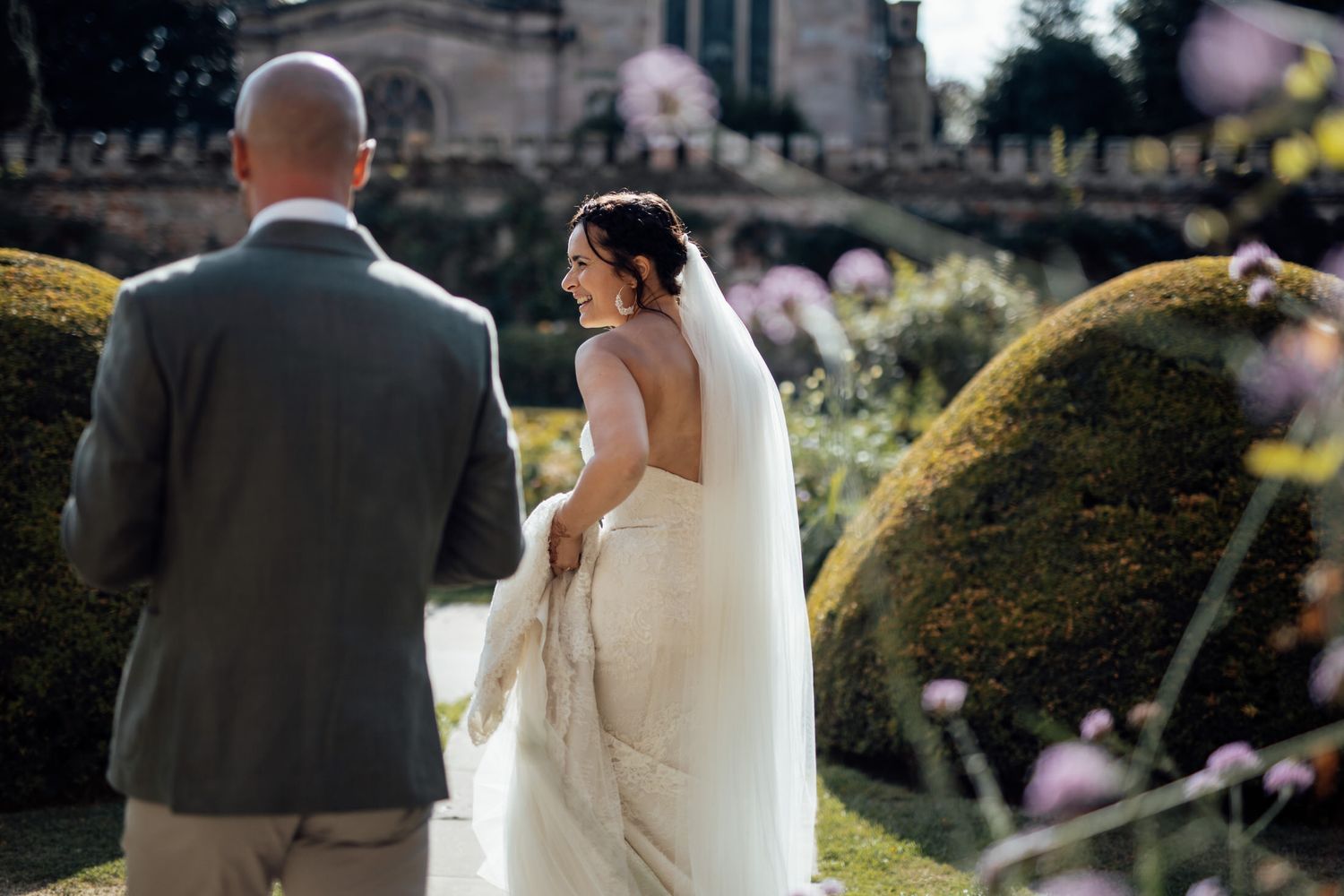 Elegant wedding couple poses together in a scenic garden setting during golden hour.