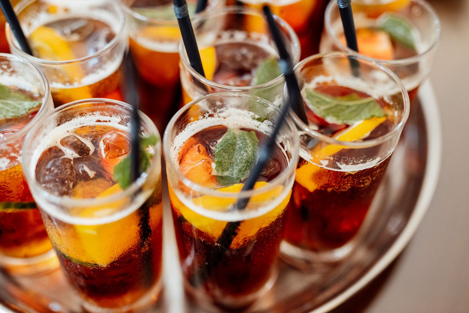 Colorful cocktails garnished with citrus slices served on elegant silver tray.