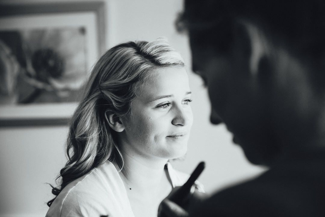 Black and white candid wedding photography captures emotional moments during preparation.