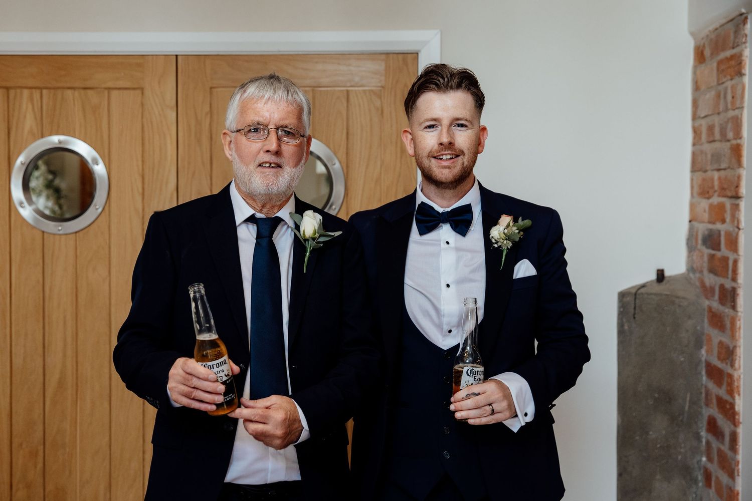 Two formally dressed guests sharing drinks and smiling at wedding celebration.