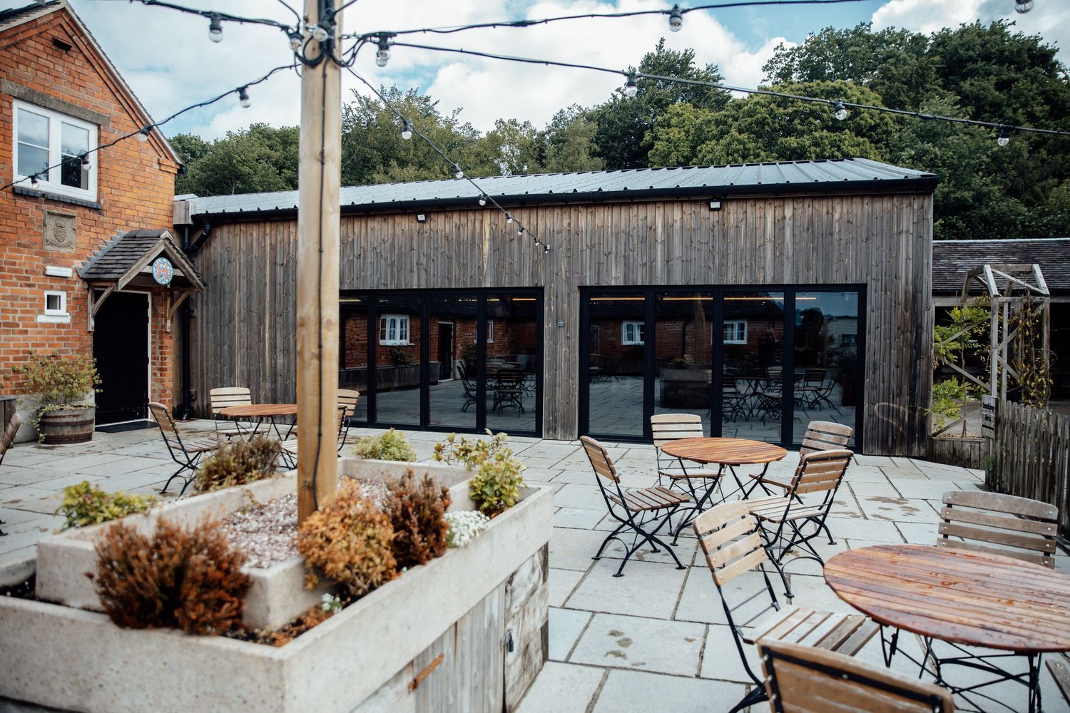 Outdoor patio venue with string lights and metal chairs set against brick buildings.