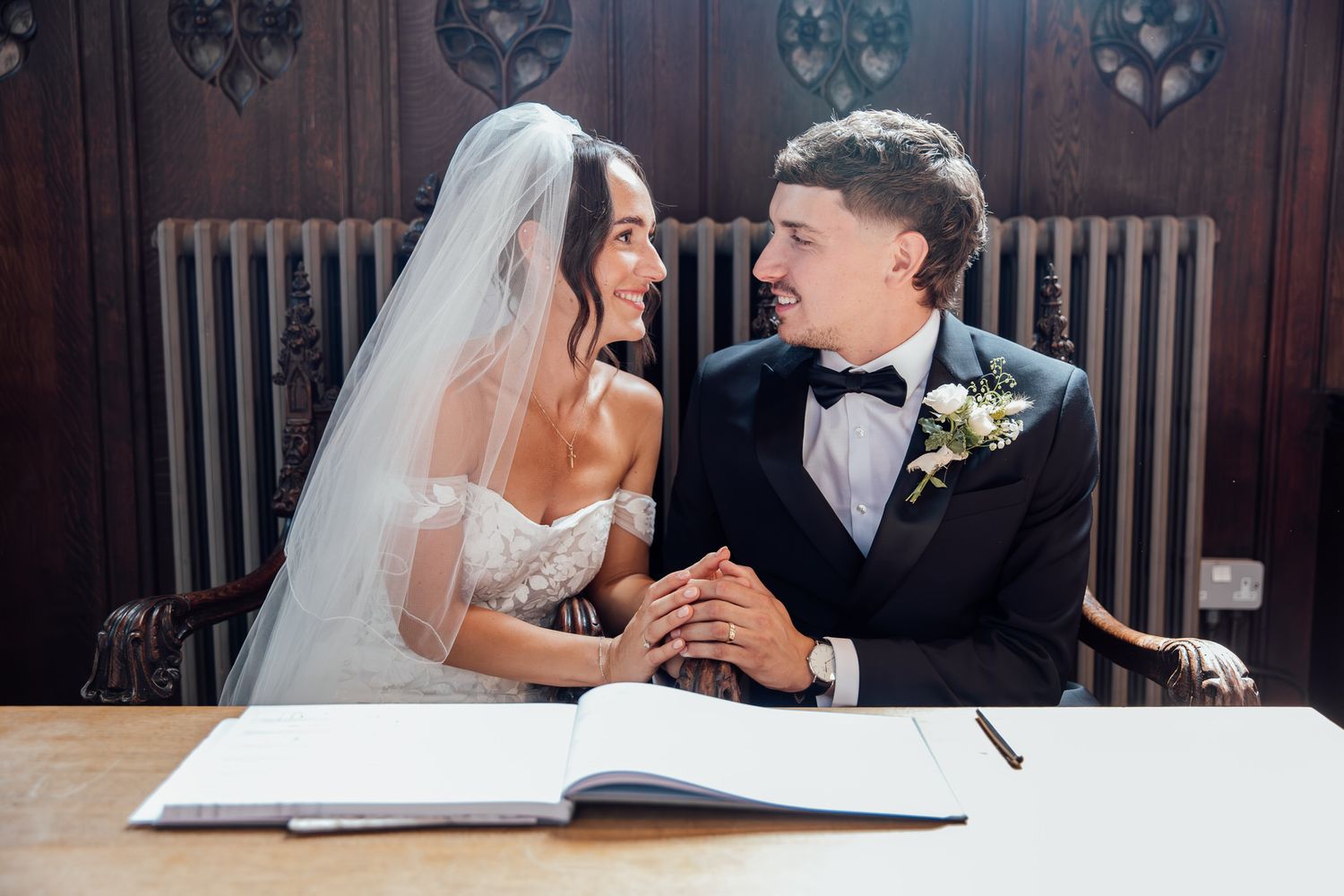 Couple signs marriage documents during intimate ceremony indoors.