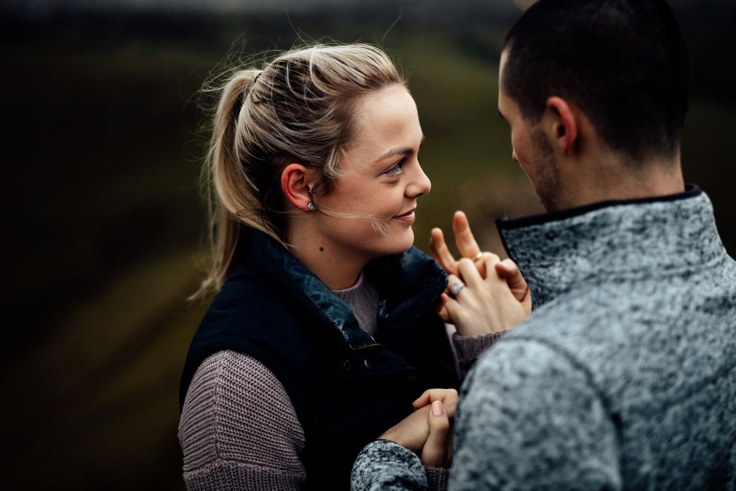 A romantic moment captured between two people in an outdoor mountain setting.